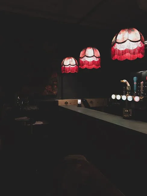 Comptoir sombre éclairé par trois lampes rouges à franges