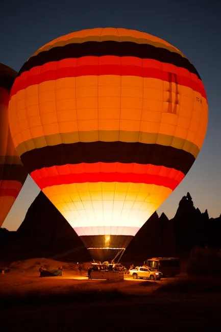 Montgolfière rayée illuminée au sol, équipage préparant le décollage