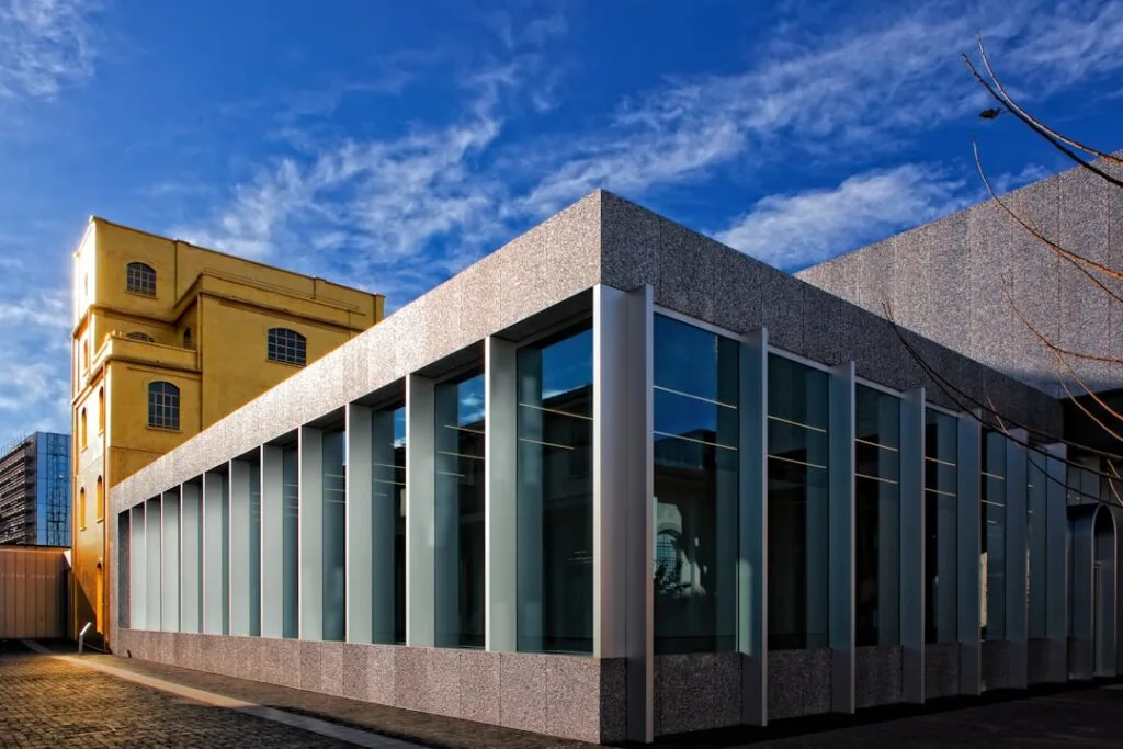 Façade vitrée moderne avec bâtiment jaune historique derrière, Milan
