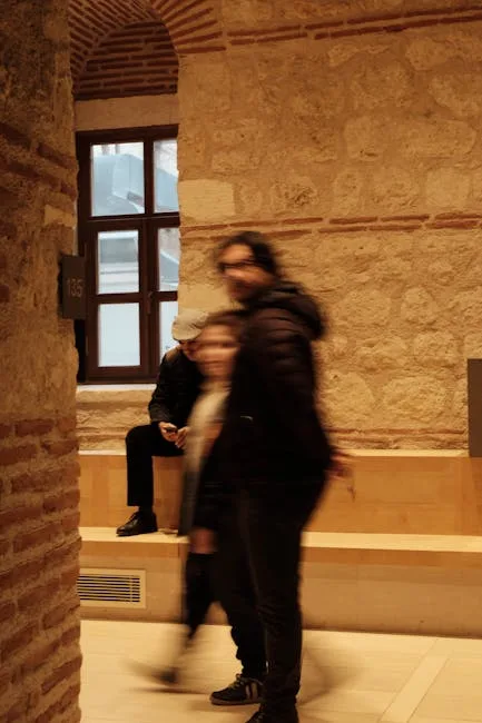 Personnes floues marchant devant un mur en pierre à l'intérieur d'un bâtiment historique