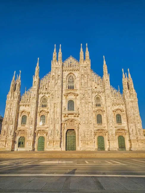 Façade sculptée du Duomo de Milan baignée par un ciel bleu