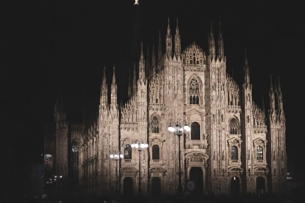 Façade du Duomo de Milan illuminée la nuit sur fond noir