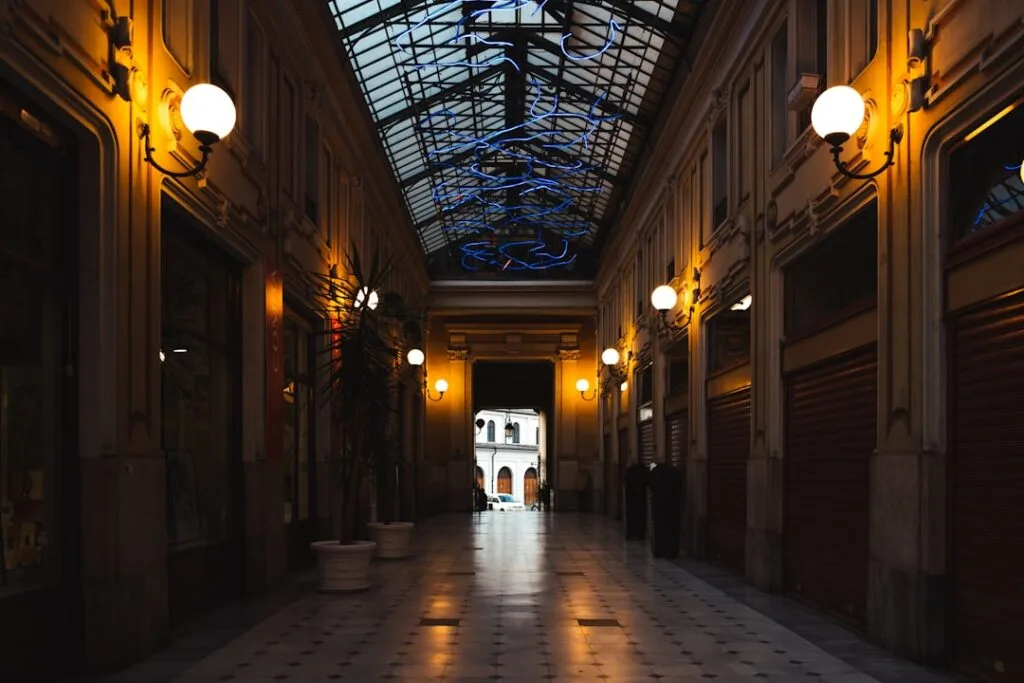 Galerie commerçante éclairée la nuit avec verrière et lampadaires à Milan