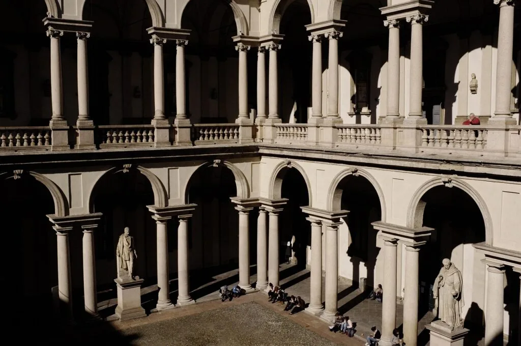 Portiques et arcades d'un palais historique de Milan baignés de lumière.