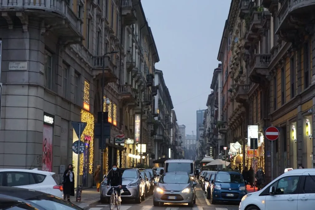 Rue commerçante de Milan au crépuscule, voitures et cyclistes