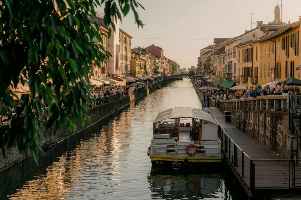 Bateau amarré dans les Navigli de Milan, terrasses animées et passants