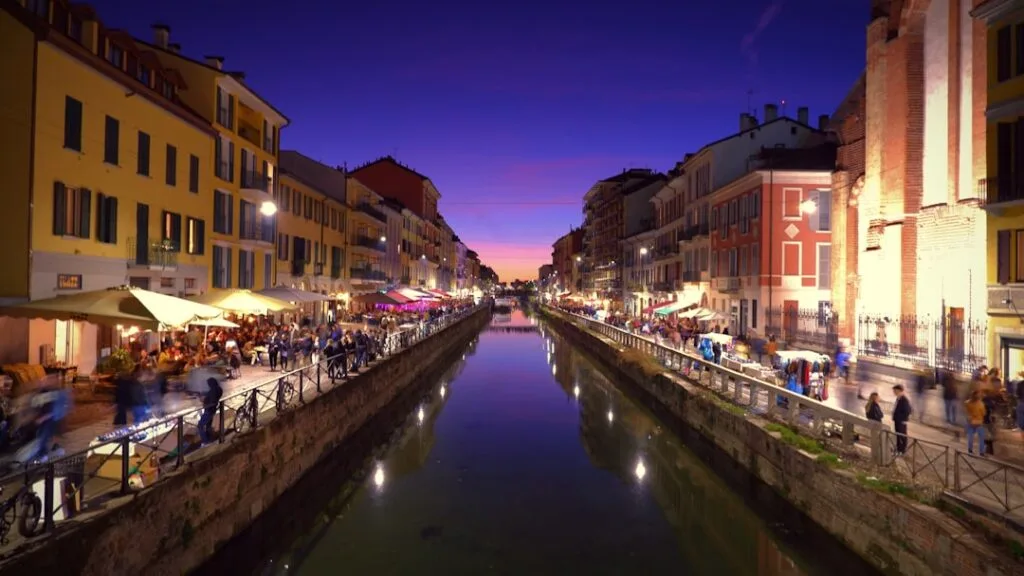 Le canal des Navigli à Milan, terrasses et passants au crépuscule.