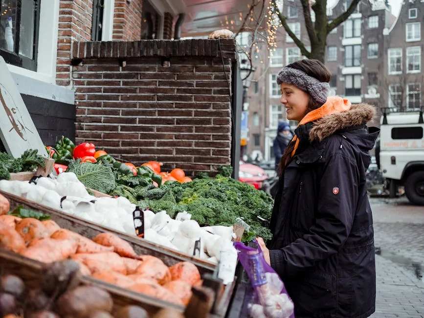 Personne en parka achetant des légumes sur un étal de marché hivernal en ville