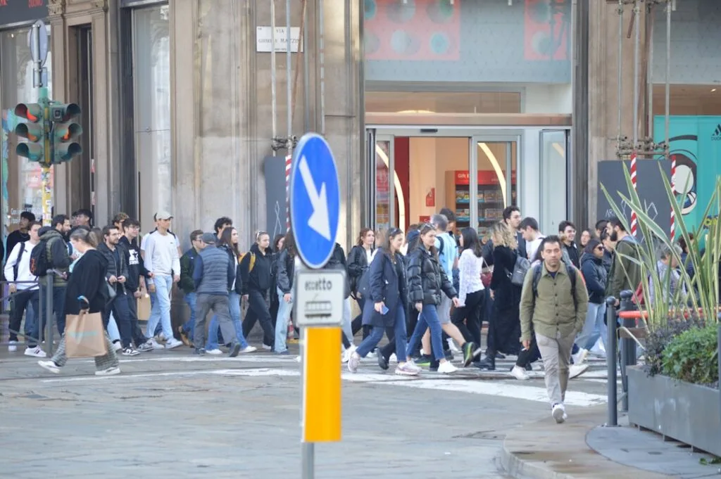 Traversée piétonne animée à Milan, foule de passants devant une boutique