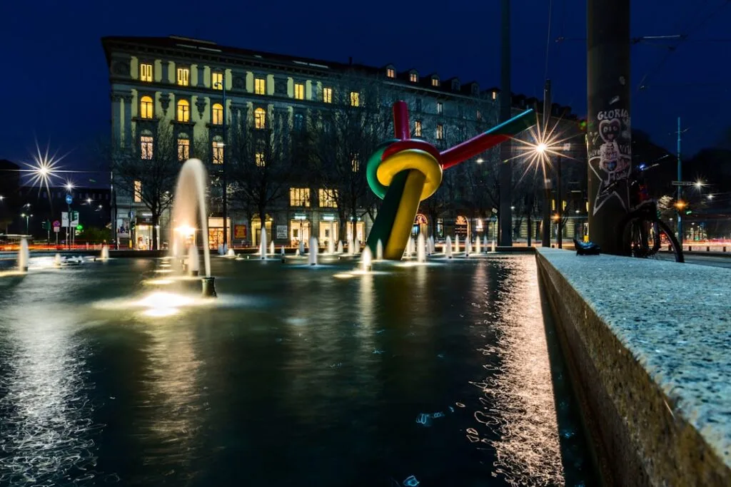 Fontaine nocturne et sculpture colorée en forme de nœud à Milan