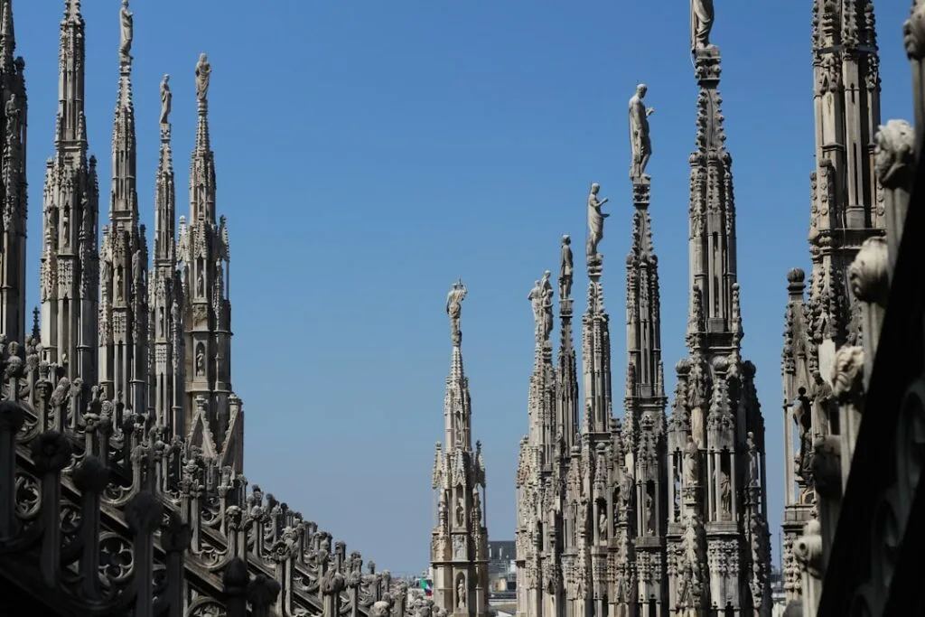 Flèches et statues gothiques du Duomo de Milan contre ciel bleu