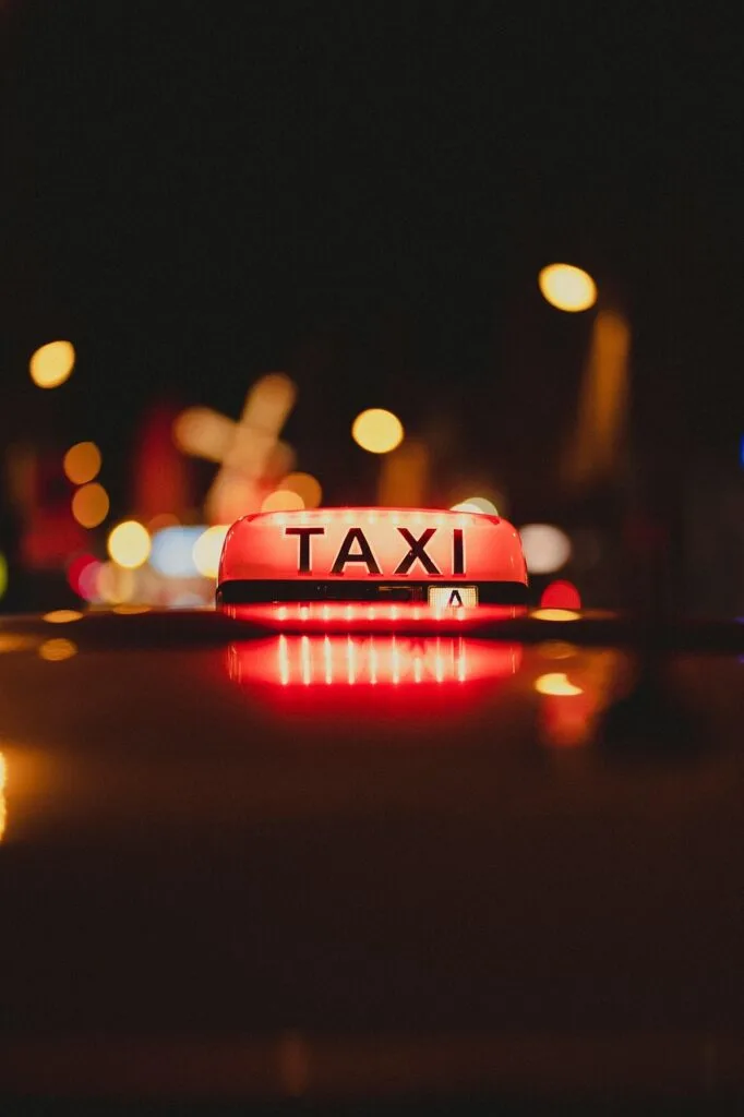 Enseigne lumineuse 'TAXI' rouge sur un toit, nuit à Milan