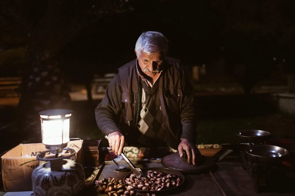 Vendeur de marrons rôtis à son stand nocturne le long des Navigli, Milan