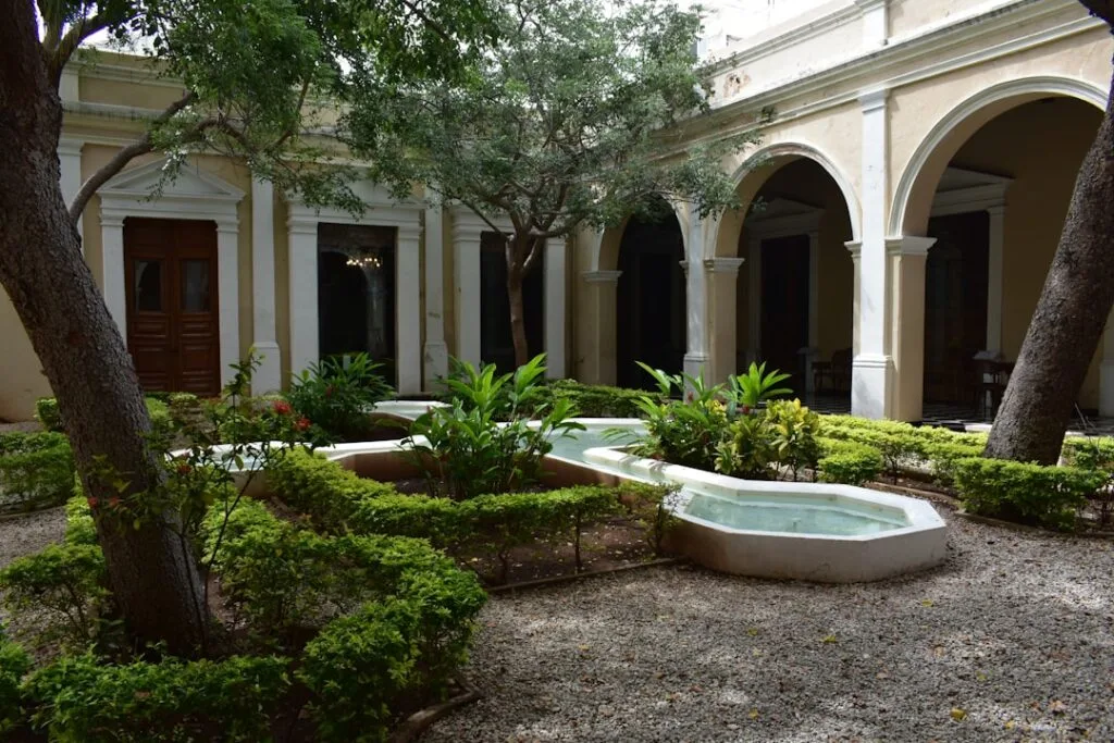Petit patio arboré avec bassin central et galeries à arcades