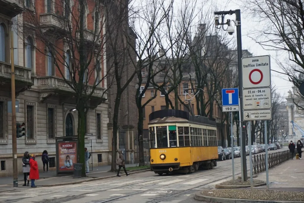 Tram jaune historique circulant dans une rue de Milan bordée d'arbres