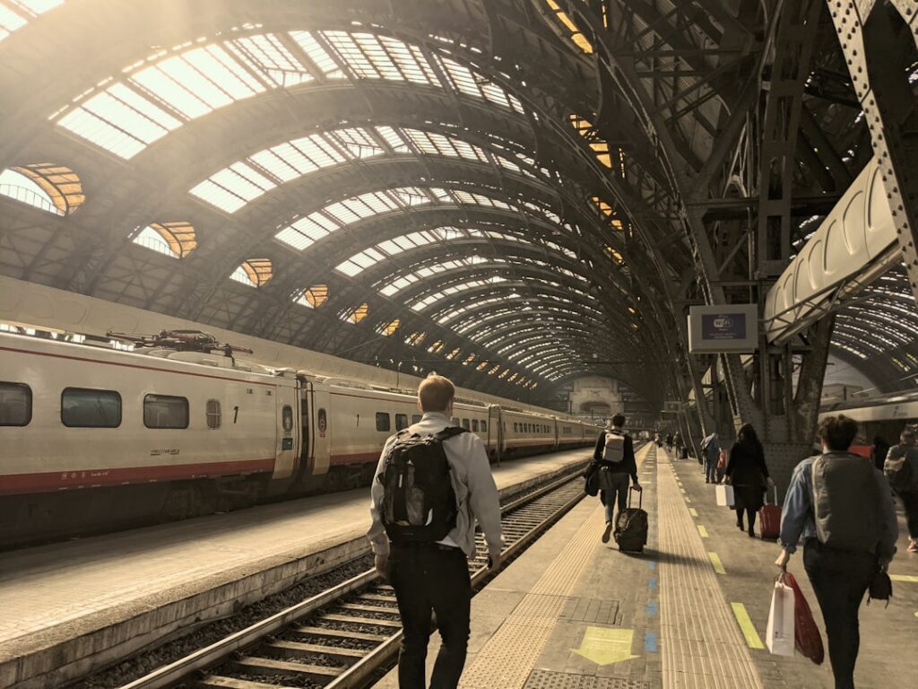 Reisende auf Bahnsteig unter gewölbter Halle des Hauptbahnhofs Mailand